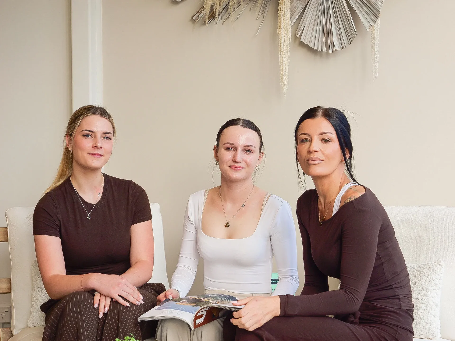 Three women sitting together holding an open magazine
