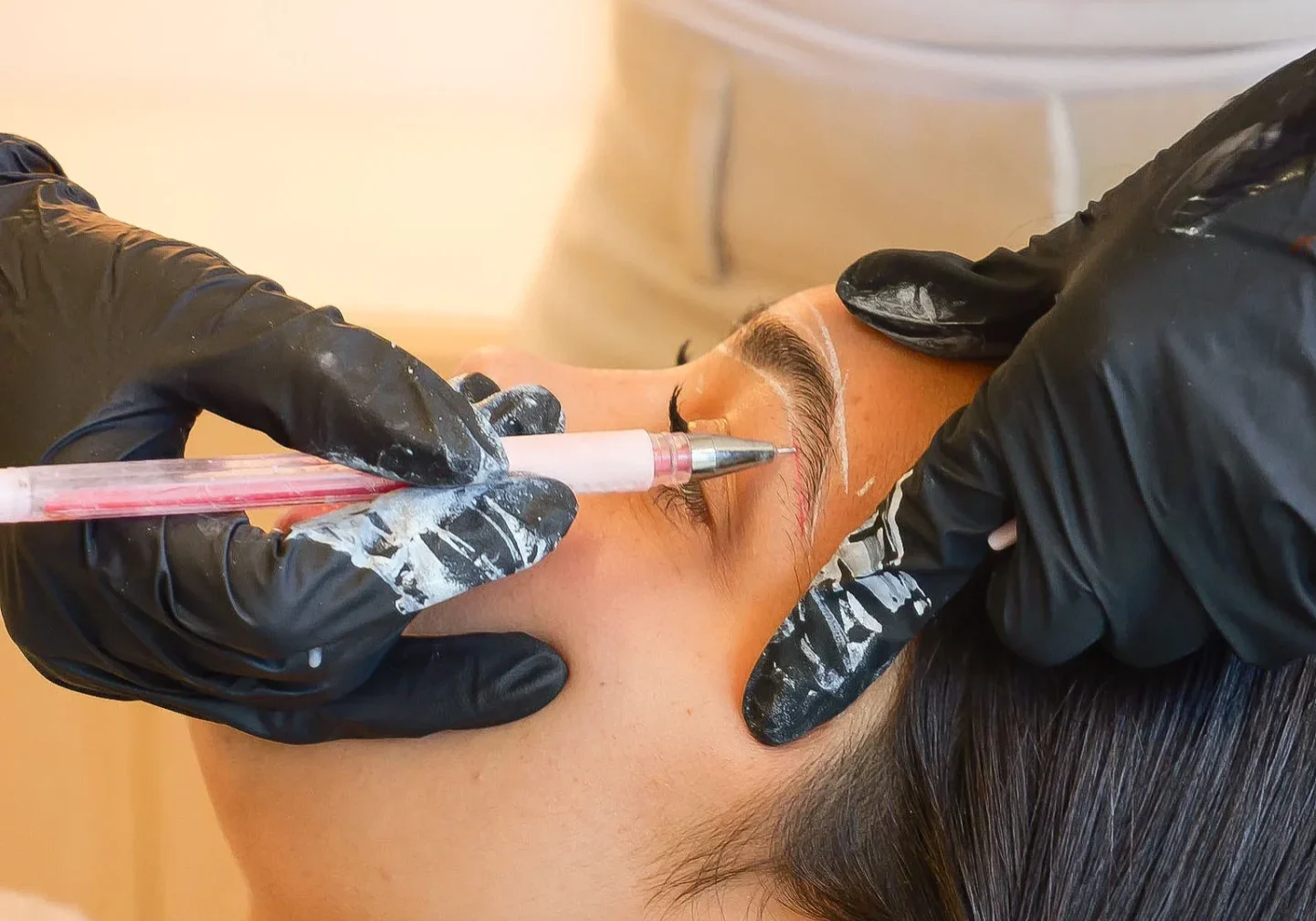 Technician performing eyebrow microblading on client