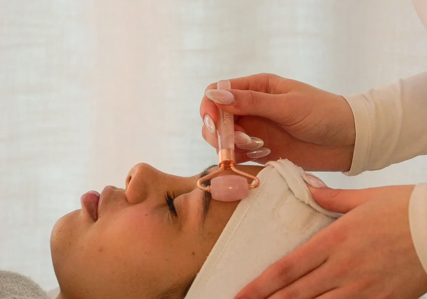 Woman receiving rose quartz facial massage at spa
