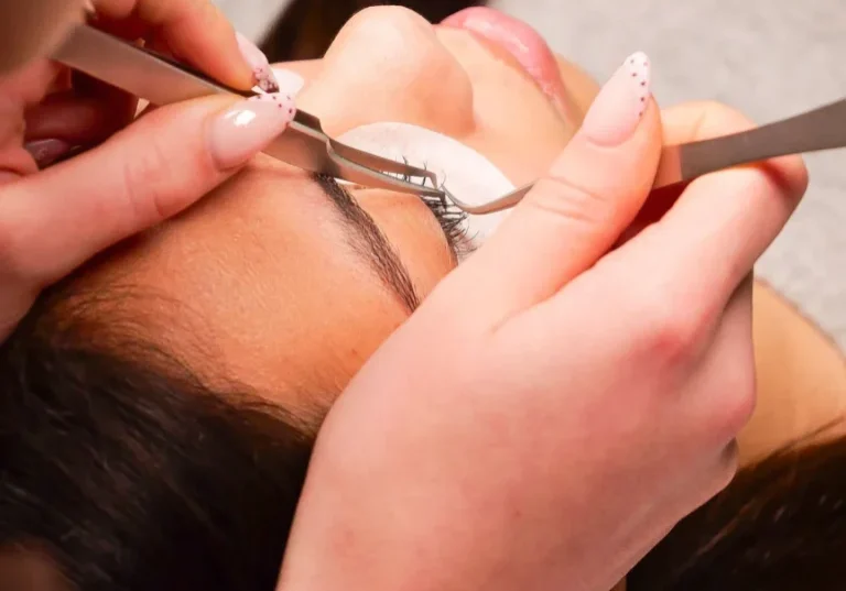 Technician applying eyelash extensions with tweezers